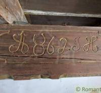 Carved inscription on a wooden beam, part of a historic family house, preserves authenticity.