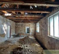 Interior of a family house with old brick walls, exposed ceiling, and windows.