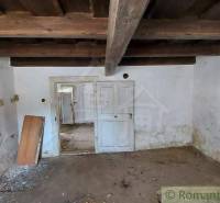An old family house with a wooden ceiling, doors, and peeling plaster in the attic space.
