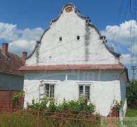A historic family house with an old roof and fence in the countryside on a sunny day.