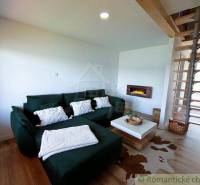 Living room of the cottage with a fireplace, sofa, and staircase in a cozy environment.