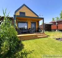 A wooden cottage in Jakubov with a terrace and green lawn, surrounded by nature.