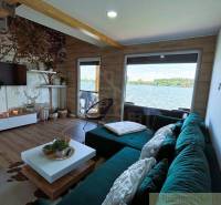 Interior of a cabin with a view of the lake, green sofa, wooden elements, decorative accessories.