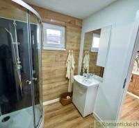 A bathroom in a cabin with a shower, sink, wooden paneling, and towels.
