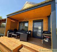 Wooden cottage in Jakubov with a terrace, garden furniture, and a grill on a grassy plot.