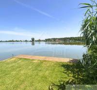 A lake near the cottage in Jakubov with wooden piers, surrounded by greenery and calm water.
