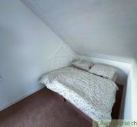 Attic room of the cottage with a double bed and a window, ideal for a romantic getaway.
