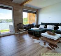 Living room in a cabin with a view of the lake, comfortable couch, and wooden floor.