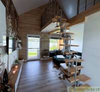 A living space with a spiral staircase, a fireplace, and a view of the lake in a cabin.