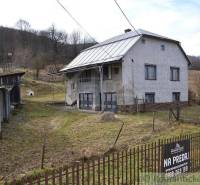 The family house stands on a sloped plot, surrounded by a garden and farm buildings.