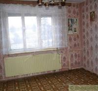 A family house with floral wallpaper, a large window, and religious paintings on the wall.