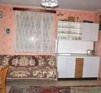 A room in a family house with a sofa, a wardrobe, and floral-patterned curtains.