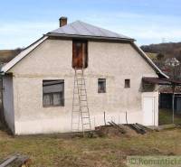 A family house with a white facade, metal roof, gardens around, a beautiful cottage.