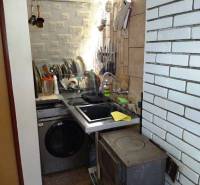 A small kitchen with a stove, a sink, and dishes on the walls in a family house.