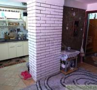 Interior of a family house, kitchen with white bricks, stone wall, and stairs in the background.