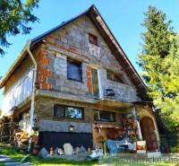 A family house with a sloped roof, surrounded by trees and decorations in the yard.