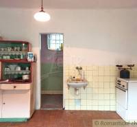 In the kitchen, there is old furniture, a wooden floor, a gas stove, and a family house.