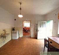 A kitchen in a family house with a wooden floor, tiles, and a dining table with chairs.