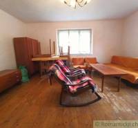 A living room in a family house with retro furniture, a rocking chair, and wooden flooring.