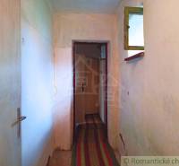 A narrow interior hallway, doors, window, carpet in a family house, the walls are white.
