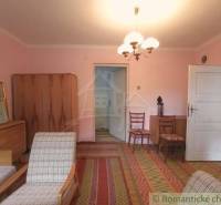 Interior of a family house with furniture and carpet, two chairs, cabinets, entrance door.