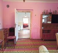 A room in a family house, retro furniture, pink walls, view into the kitchen.
