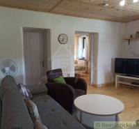 A living room in a cottage with a sofa, television, and wooden ceiling, ideal for relaxation.
