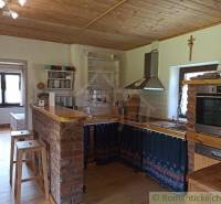 A kitchen with a wooden ceiling, a brick counter, complemented by equipment suitable for a cabin.