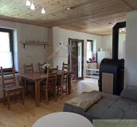 A rustic cottage with a wooden ceiling, a dining table, and a fireplace in a cozy setting.
