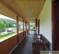 A long wooden porch at the cottage, overlooking the garden and surrounding hills.