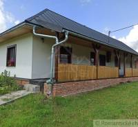 I see a traditional cottage with a wooden porch and an elevated brick foundation.