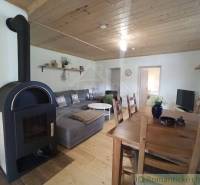 The interior of a cabin with a fireplace, wooden ceilings, a cozy sofa, and a dining table.