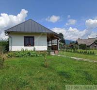 A village cottage with a tin roof, rustic style, beautiful garden, and surrounding nature.