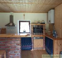 Rustic kitchen with a brick counter in the interior of a cottage, wooden elements, and a stove.