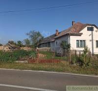 A family house by the road with fencing, an old fence, and a neglected garden.
