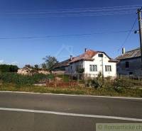A country house, an older house with a metal roof, a fenced plot by the road.