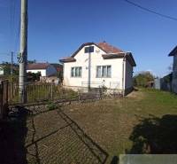 A family house with a lawn, a fence, and an electric pole in the countryside.