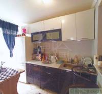 A kitchen in a family house with a comfortable corner window and dark kitchen furniture.