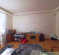 Room in a family house with light walls and furniture, bottles on the shelf.