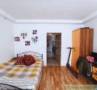 A bedroom in a family house with wooden flooring, decorative wallpaper, and storage space.