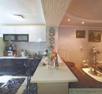 The family house has a cozy kitchen with a bar counter, complemented by decorations and paintings.