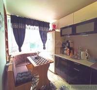 A kitchen in a family house with a dining table, bench, coffee maker, elegant curtains, and decorations.