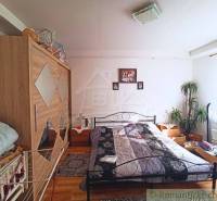 Bedroom in a family house with a bed, wardrobe, and plant, wooden floor.