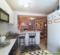 A kitchen with bar stools, a dishwasher, and decorations in a family house.