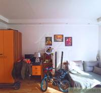 A room in a family house with an orange wardrobe, a couch, and a bicycle, ideal for a family.