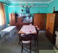 A dining room in a family house with wooden furniture, a table, and a blue wall.