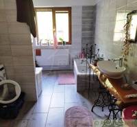 Bathroom, sink and bathtub, towel washer, lit by natural light in a family house.