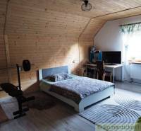 Attic room with wooden paneling, a bed, a desk, and exercise equipment in a family house.