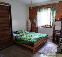 Bedroom in a family house with wood paneling, a bed, and a wardrobe.