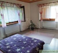 A family house with a bright bedroom, floral curtains, and wooden windows.